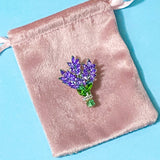vintage inspired bunch of lavender sparkly metal brooch in a pink velvet bag on a blue background