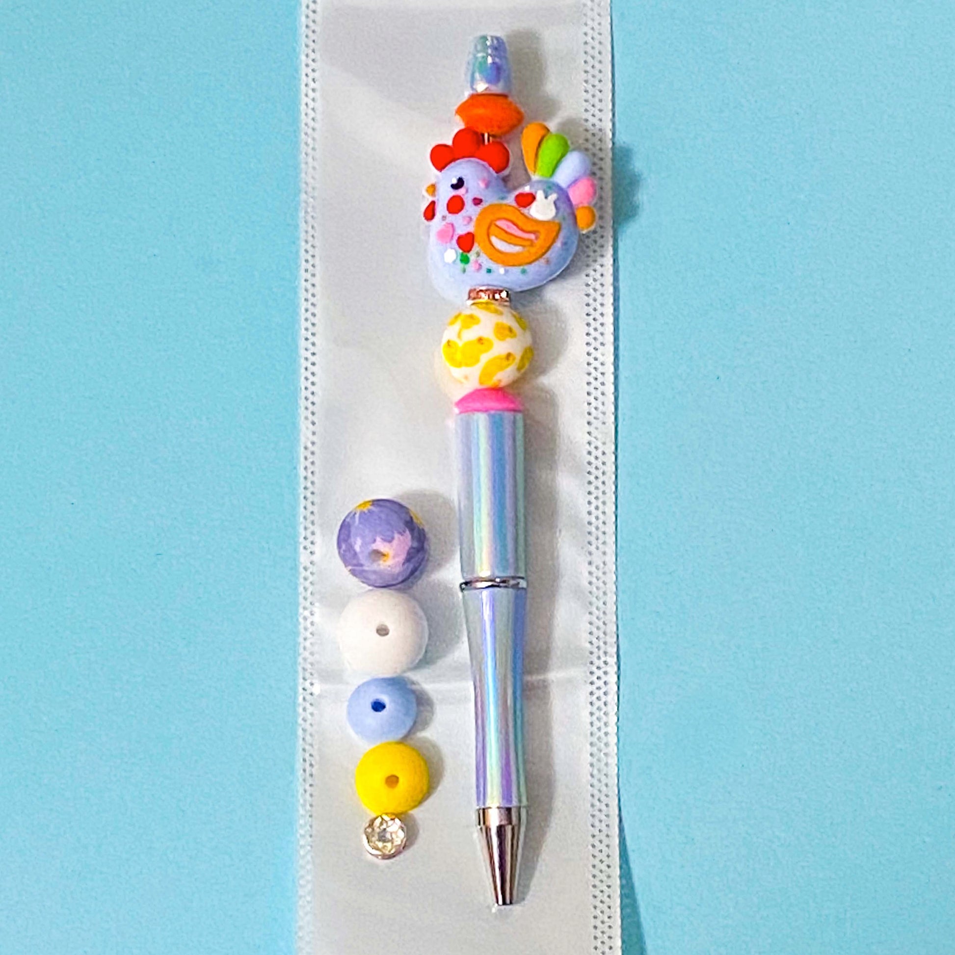 large colourful cockerel chicken beaded pen diy kit on a blue background