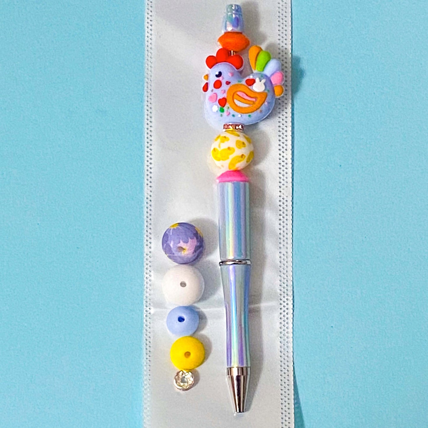 large colourful cockerel chicken beaded pen diy kit on a blue background