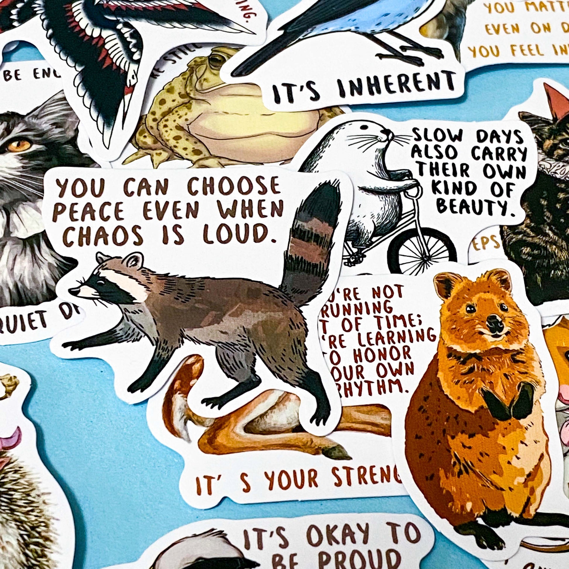 set of 50 animal positive quote stickers with affirmations featuring illustrated wildlife including raccoons, seals and birds on a soft blue background