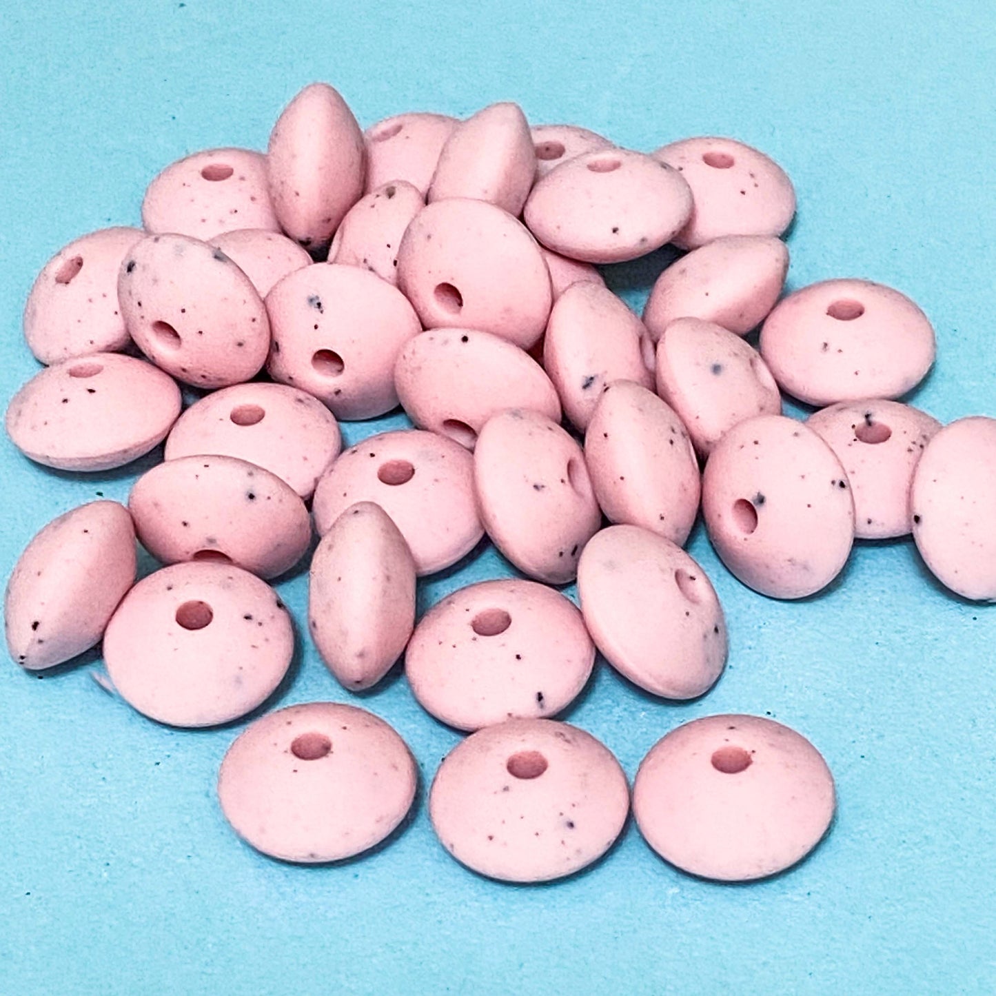 pastel pink speckle pattern silicone spacer beads on a blue background