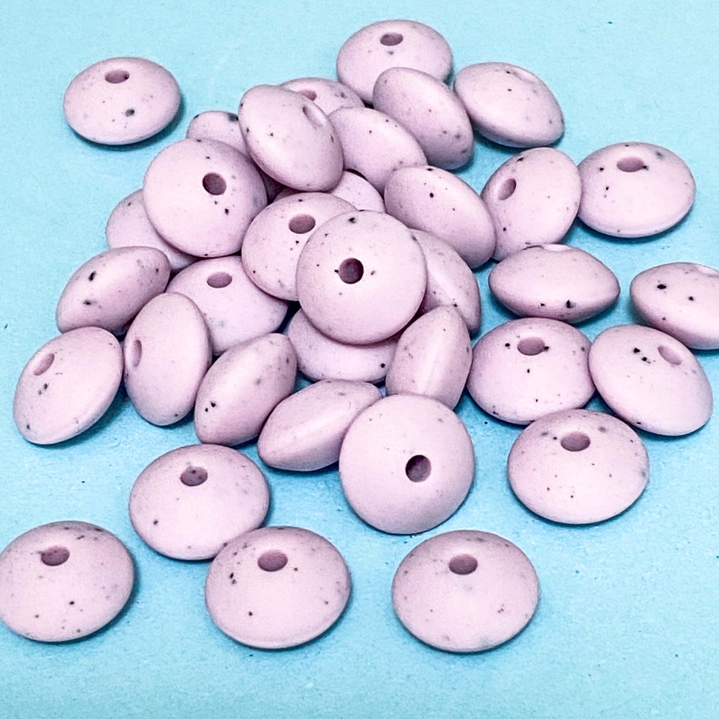 pastel lilac speckle pattern silicone spacer beads on a blue background