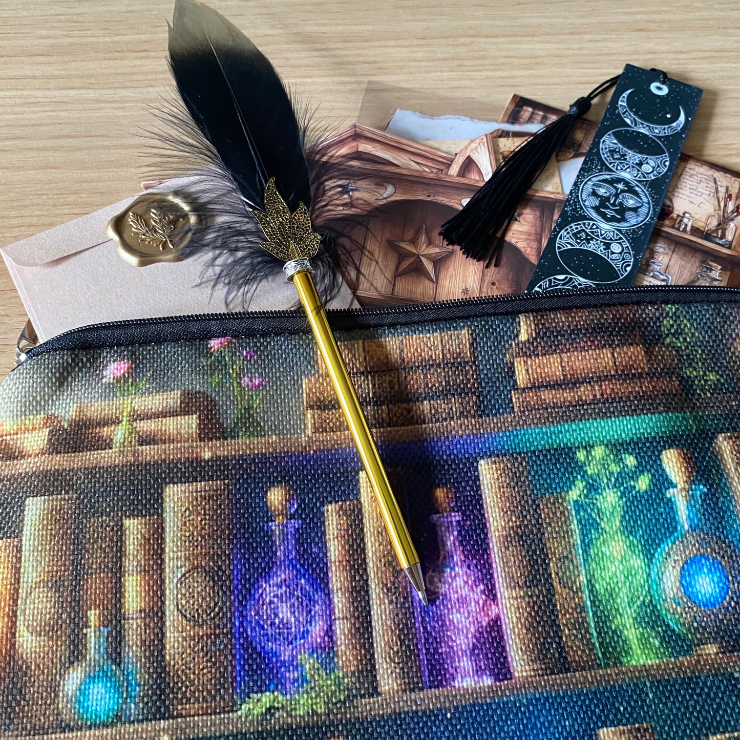 celestial moon phase bookmark with black tassel and black feather ballpoint pen on a canvas potions bag